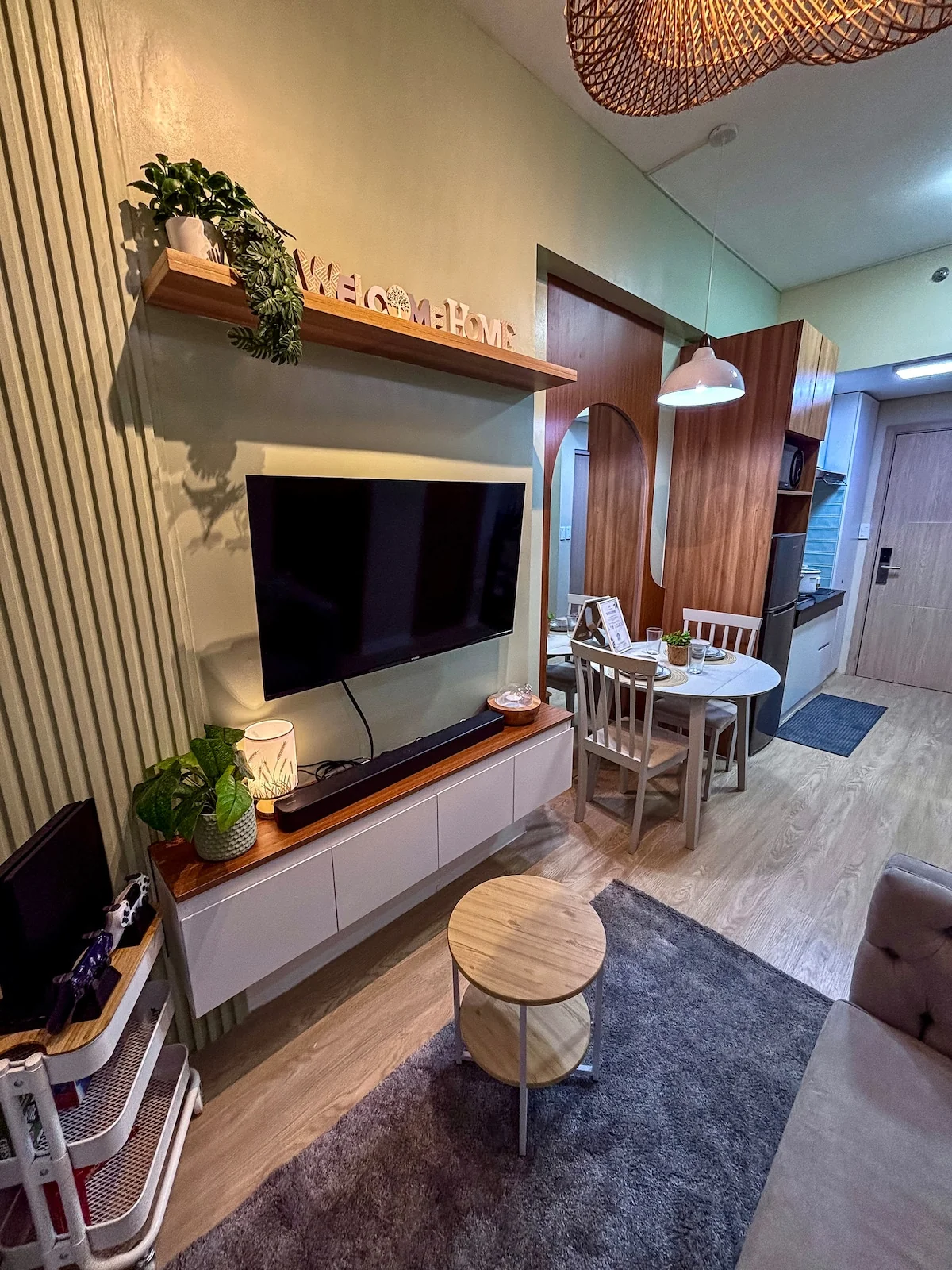Living and dining area with a wall-mounted TV, wood details and a round table