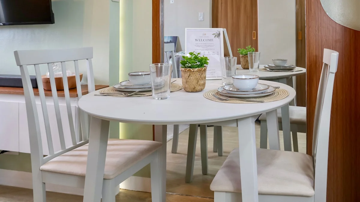 Round dining table with white chairs, place settings and glasses